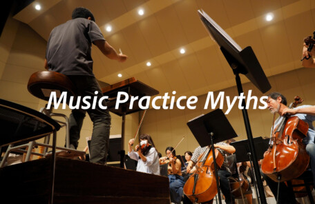 指揮者がオーケストラを指導しているリハーサル風景。音楽練習における思い込みや固定観念を問い直すイメージ。