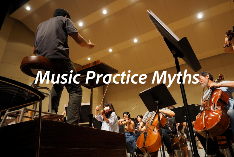 指揮者がオーケストラを指導しているリハーサル風景。音楽練習における思い込みや固定観念を問い直すイメージ。