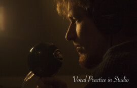 マイクに向かって歌う男性の横顔と「Vocal Practice in Studio」の文字が入ったスタジオ風景