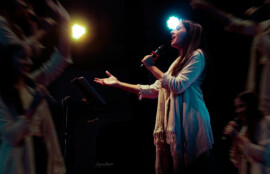 ステージ照明の中でマイクを持ち歌う女性シンガー