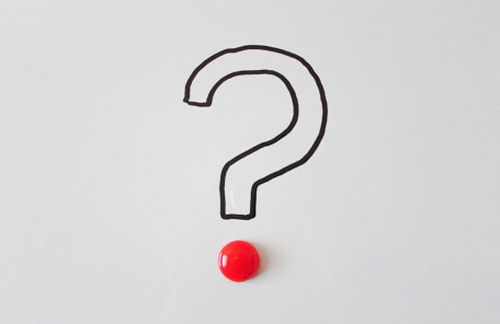 ホワイトボードに描かれたクエスチョンマークと赤いマグネット