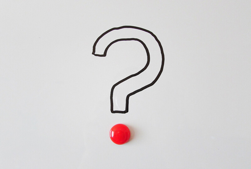 ホワイトボードに描かれたクエスチョンマークと赤いマグネット