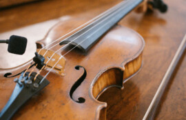 木製テーブルの上に置かれたバイオリンと弓のクローズアップ