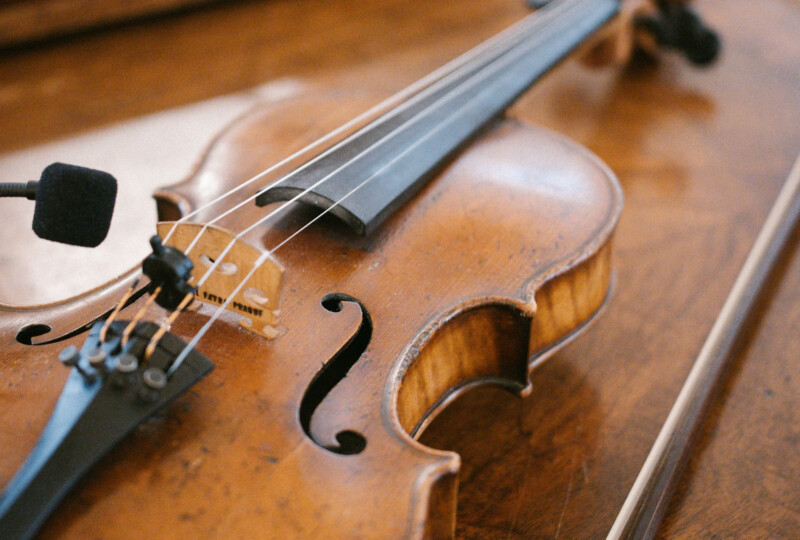 木製テーブルの上に置かれたバイオリンと弓のクローズアップ